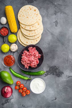 Geleneksel ev yapımı tako malzemeleri et, salsa, biber, domates, avokado, mısır, gri arka planda tortilla, metin için boşluk ile üst görünüm