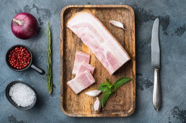 Pastırma pancetta. Gri desenli arka planda kesilmiş ve kesilmiş otlarla dilimlenmiş..