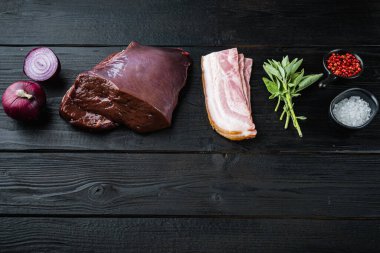 Domuz pastırmalı sığır ciğeri ve siyah ahşap kaplamalı soğan..