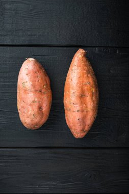 Çiğ patates, siyah ahşap arka planda, düz bir şekilde kopyalanmış..