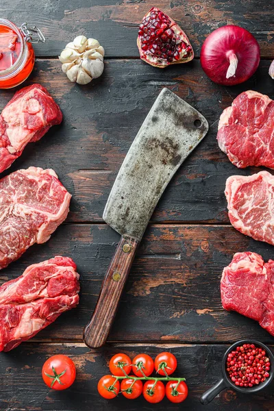 Meat beef steaks frame concept, with different steak cuts and butcher cleaver in frame on dark old wooden table  top view.