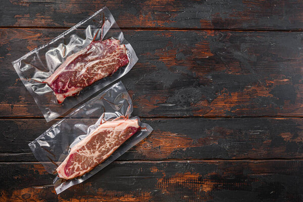Top blade beef steak for sous vide cooking on dark old wooden table, top view with space for text.