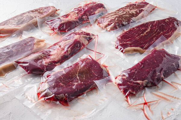 Set  of  vacuum packed organic raw beef steaks  alternative cuts over white background, side view