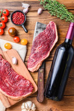 Picanha organik biftekleri eski Amerikan kasap satırı üzerine baharatlar ve ahşap masada kırmızı şarap şişesi. Üst görünüm kapat.