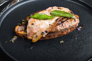 Ekmeğin üstünde domuz pastırması ve soğan. Siyah yüzeyde tabakta pişmiş yemek..