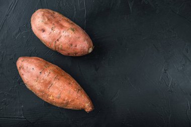 Siyah arkaplanda tatlı patates veya batat, metin için boşluk ile üst görünüm.