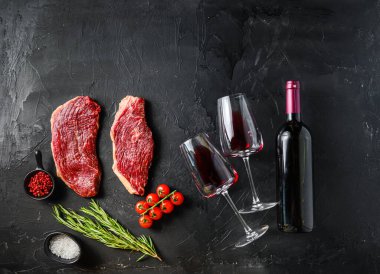Çiğ Picanha bifteği ve kırmızı şarap bardakları. Siyah arka planda düz bir alan. Mesaj için. Büyük boyut