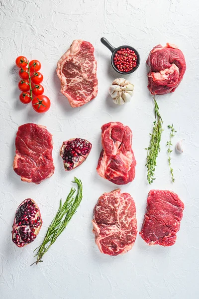 Beef cuts Chuck eye roll, top blade, rump steakwith  herbs and pomegranate. Organic meat. White textured background. Top view