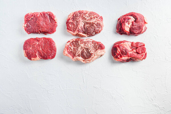 Raw set of alternative beef cuts Chuck eye roll, top blade, rump steak. Organic meat. White textured background. Top view with space for text