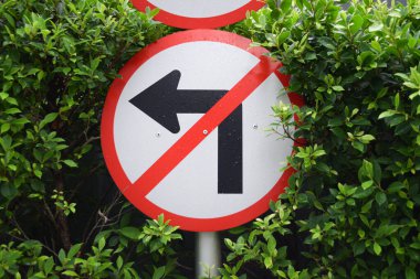 Bahçe arka planında sola dönmeyin. Yuvarlak trafik levhası.