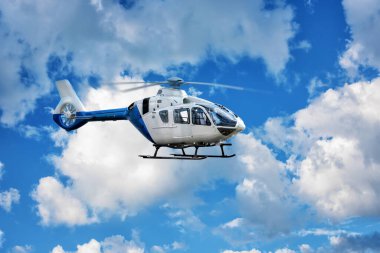 Helikopter yazın mavi bulutlu gökyüzünün arka planında havalanıyor..