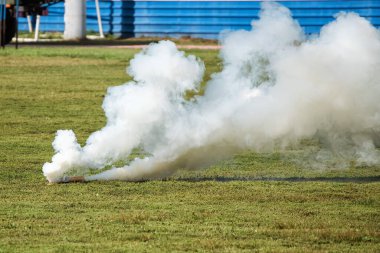 Yazın yeşil çimlerde beyaz duman bombası.