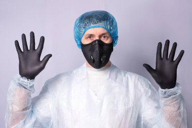 Solunum cihazı ve ameliyat önlüğü giymiş bir doktor çalışmaya hazır..