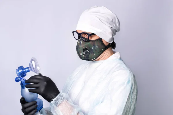 A doctor wearing respirator mask with oxygen ambu bag for inhaling some air by a patient.