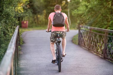 Yazın bir köprüde, parkta bisiklet süren bir çocuk..