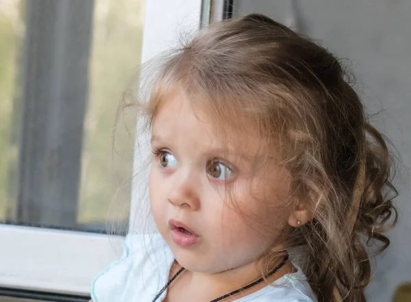 Uma Menina Loira Bonita Fica Janela Olha Surpresa — Fotografia de Stock