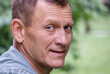 Gülümseyen orta yaşlı bir adamın yakın portresi.