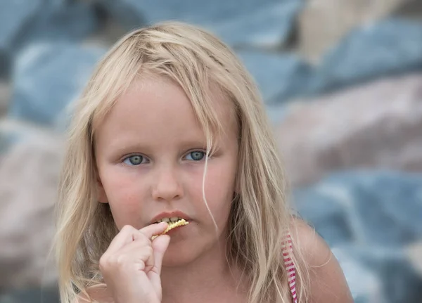 可爱的金发碧眼的6岁小女孩吃着自然界中的薯片 — 图库照片