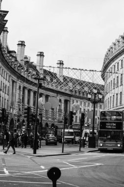 Londra 'daki Piccadilly Caddesi' nin fotoğrafı. Arabaları, otobüsleri ve etrafta yürüyen insanları var.