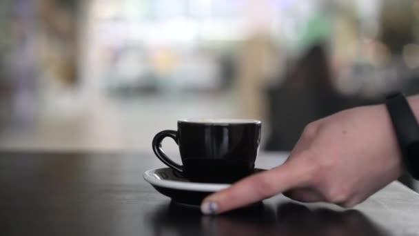 Hand zetten een zwart kopje op de tafel — Stockvideo