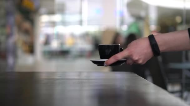 Hand zetten een zwart kopje op de tafel — Stockvideo