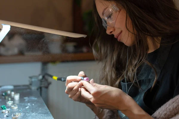 girl master processes the metal plate in the home workshop