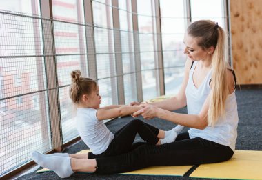 Anne ve kızı birlikte farklı egzersizler yapıyorlar.