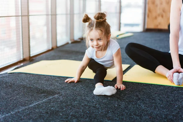 Маленькая девочка повторяет упражнения для своей матери — стоковое фото