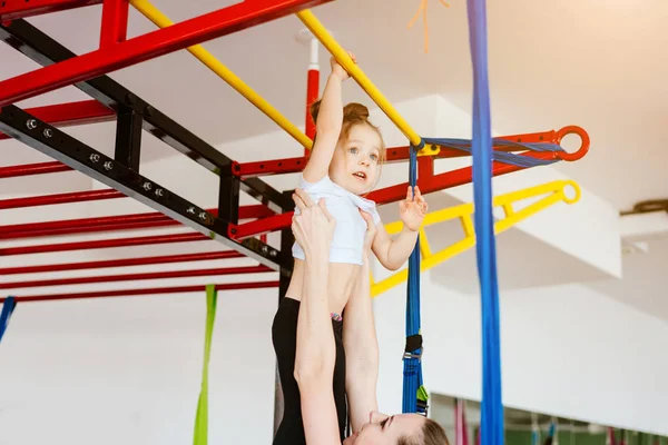 Petite fille suspendue sur la barre transversale, maman soutient — Photo