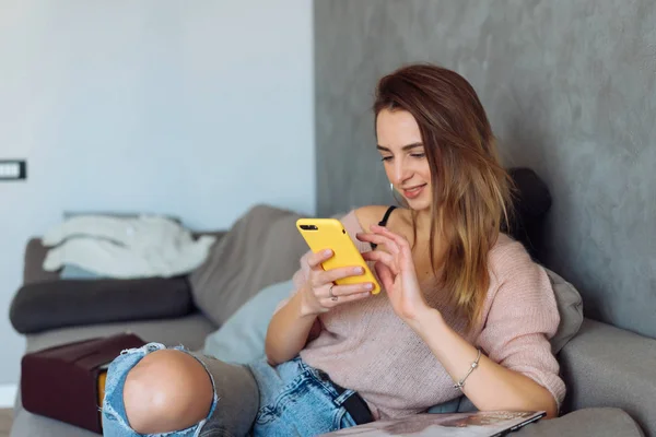 Hübsche Mädchen mit ihrem Smartphone auf der Couch zu Hause — Stockfoto