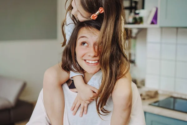 Krásný malý dcera piggybacking na ji šťastný matka — Stock fotografie