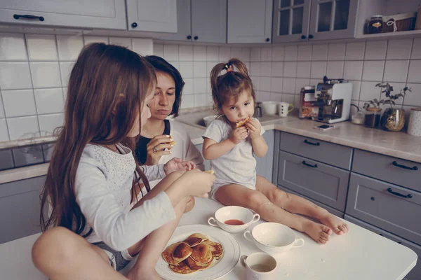 Mom and two daughters eat pancakes — Stock Photo, Image