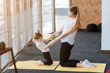 Anne ve kızı birlikte farklı egzersizler yapıyorlar.