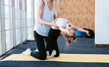 Anne ve kızı birlikte farklı egzersizler yapıyorlar.