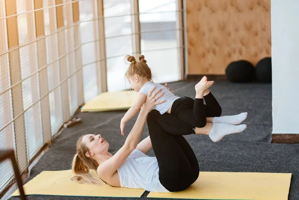 Мама и дочь вместе выполняют различные упражнения — стоковое фото