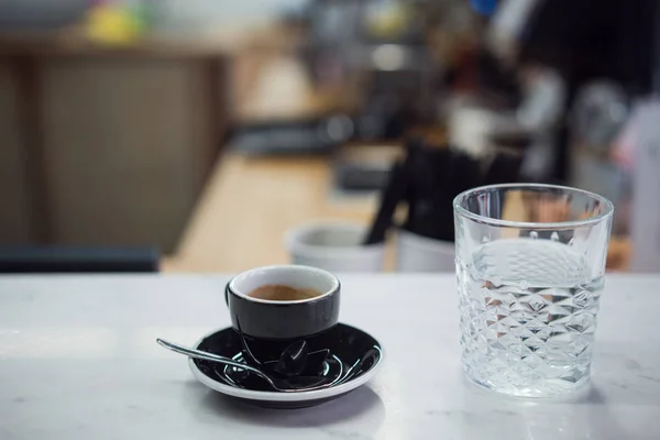 Koffiemok en een glas water op een tafel — Stockfoto