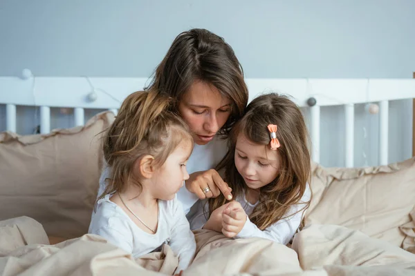 Anne ve iki kızı yatakta çizmek — Stok fotoğraf