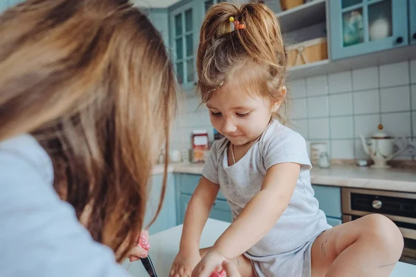 Two little girls in the kitchen sitting on the table. — Stock Photo, Image