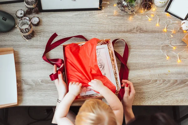 Frau wickelt Geschenk in Papier mit roter Schleife. — Stockfoto