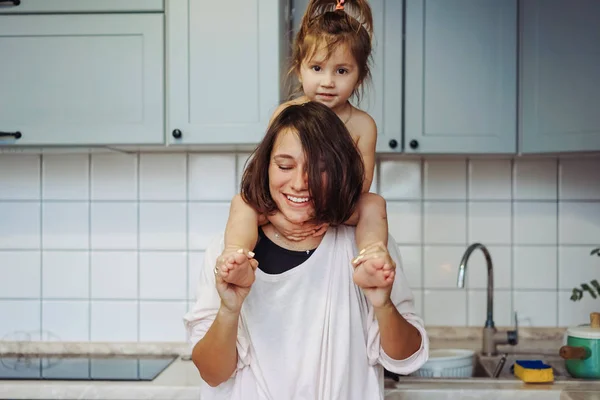 Beautiful little daughter piggybacking on her happy mother — Stock Photo, Image