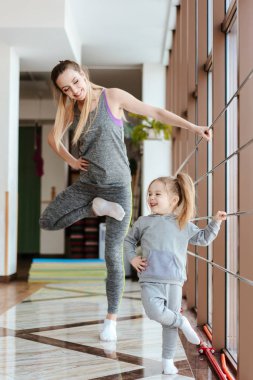 Anne ve kızı birlikte farklı egzersizler yapıyorlar.