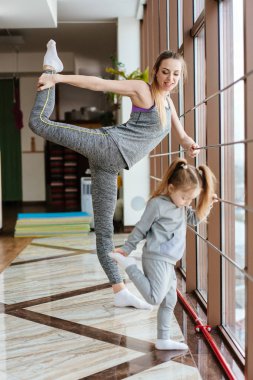 Anne ve kızı birlikte farklı egzersizler yapıyorlar.