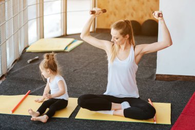 Anne ve kızı birlikte farklı egzersizler yapıyorlar.