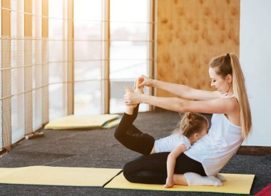 Anne ve kızı birlikte farklı egzersizler yapıyorlar.