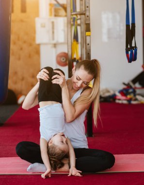 Anne ve kızı birlikte farklı egzersizler yapıyorlar.