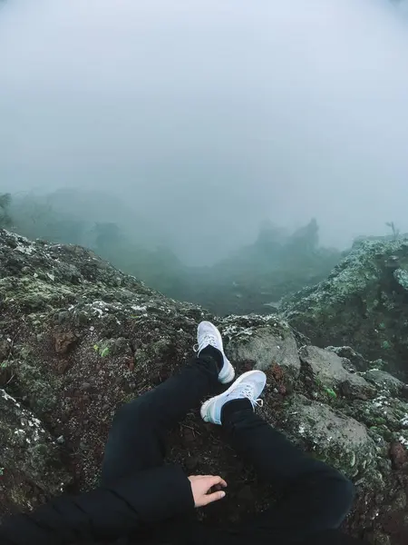 Hombre en el acantilado mira la niebla — Foto de Stock