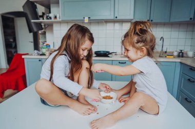 Mutfakta masada oturan iki küçük kız..