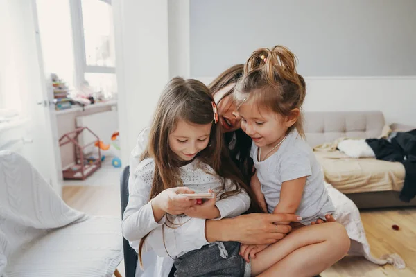 Maminka a dvě dcery hledají smartphone — Stock fotografie