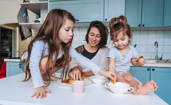 Mom and two daughters eat pancakes — Stock Photo, Image