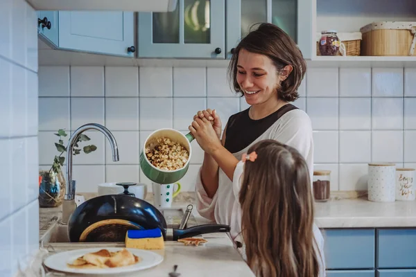 En liten söt flicka och hennes mamma i köket hemma — Stockfoto